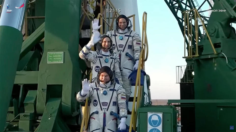 Soyuz commander Aleksey Ovchinin, bottom, NASA's Don Pettit, middle, and cosmonaut Ivan Vagner, top, wave to supporters at the base of their Soyuz rocket before taking an elevator to the top of the gantry to strap in for launch. (NASA) / Credit: NASA/Roscosmos