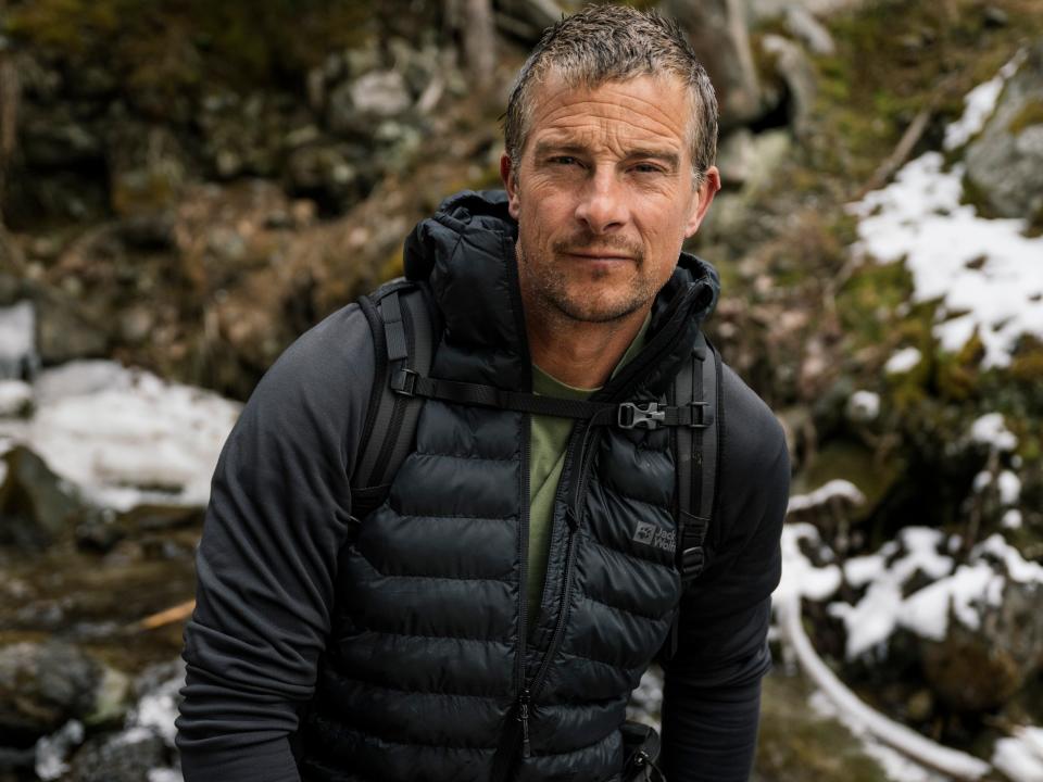 Bear Grylls stands in the wilderness.