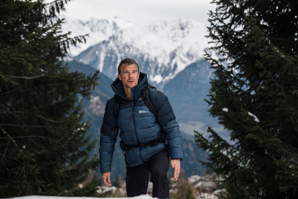 Bear Grylls against a backdrop of mountains.