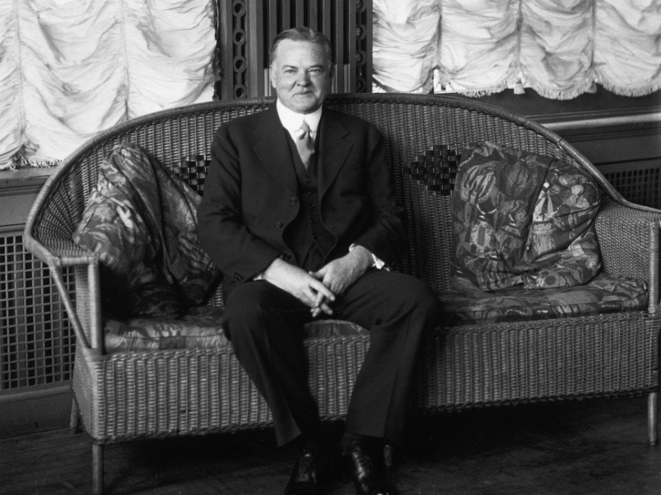 Herbert Hoover sits on a wicker couch in 1928.