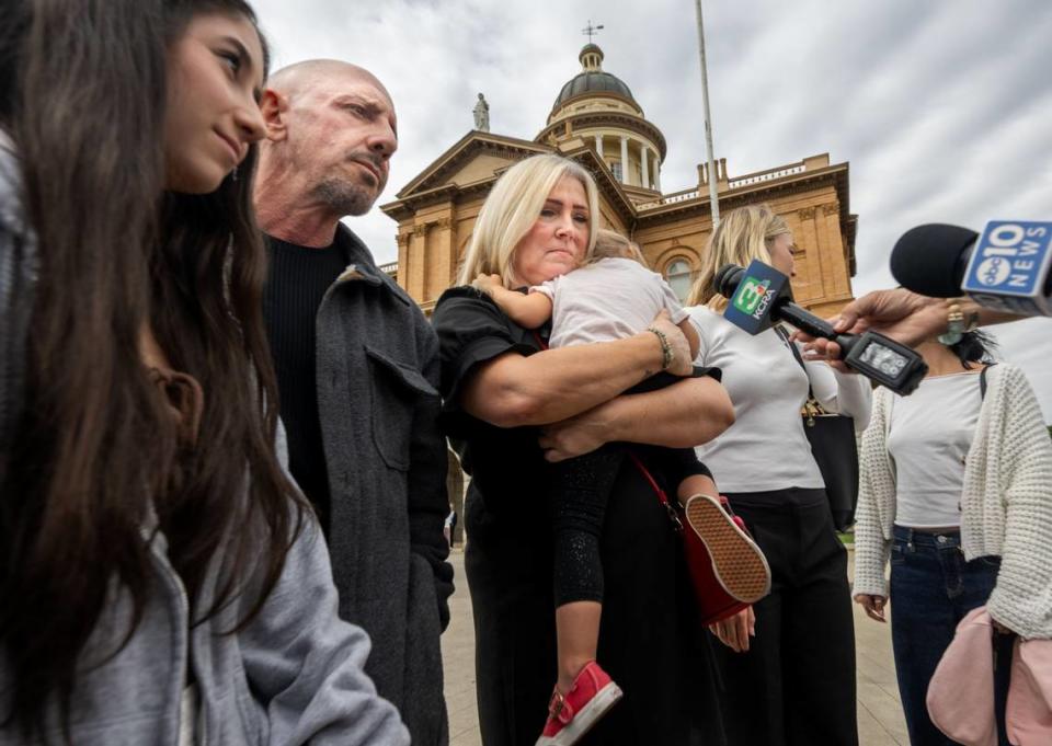 Elizabeth Dillender, center, hugs her two-year-old granddaughter Indigo Kade Webb while speaking to the media on Tuesday after the murder conviction of Carson David Schewe in Placer Superior Court in Auburn. Schewe sold fentanyl-laced pills to Kade Kristopher Webb, Dillender’s son and Indigo’s father. Kurt Webb, Kade’s father, stands at left.