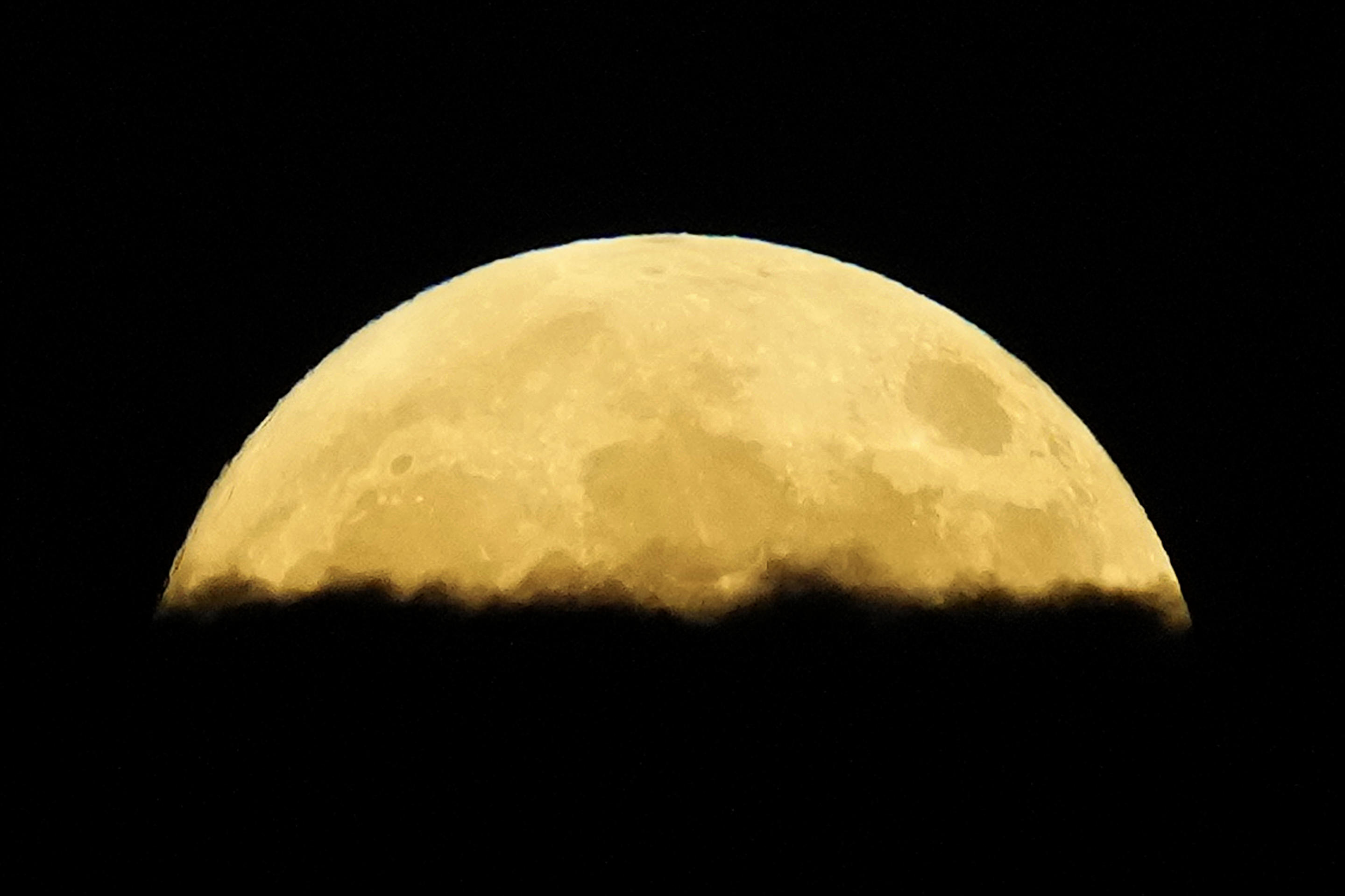 A supermoon rises behind clouds over Larnaca international airport in the eastern Mediterranean island of Cyprus, Sept. 17. (Petros Karadjias/AP)