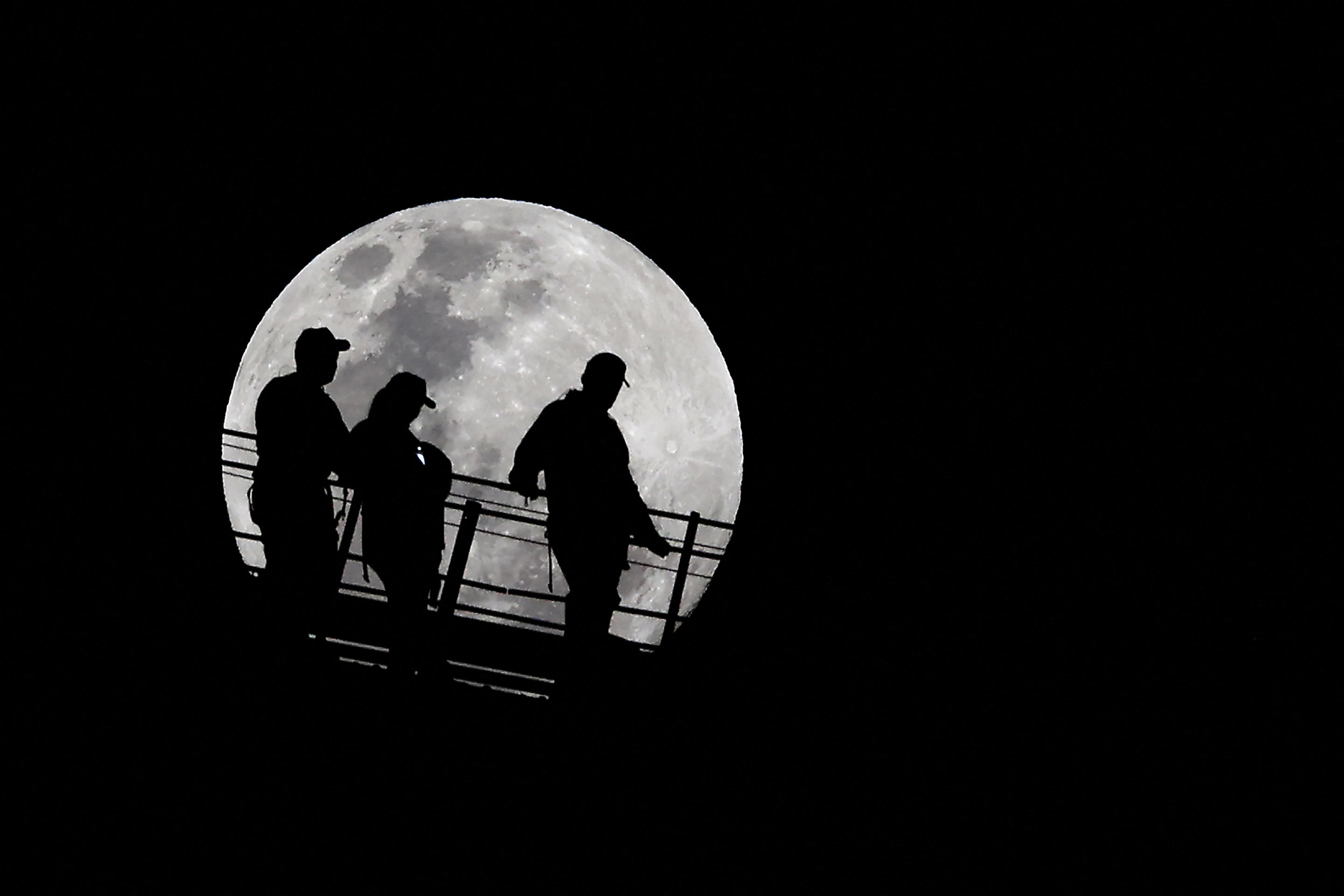 Climbers are silhouetted against the full moon near the summit of the Sydney Harbour Bridge on Sept. 17. (Saeed Khan/AFP via Getty Images)