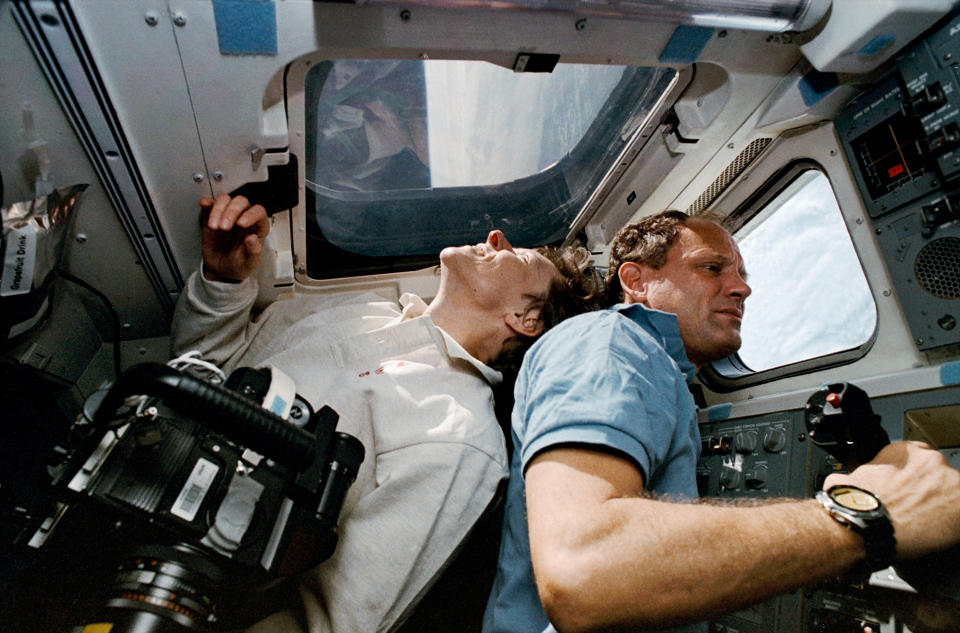 Roberta Bondar, STS-41 payload specialist, smiles as she looks out the overhead window of the space shuttle Discovery, back to back with mission specialist Norm Thagard in 1992.