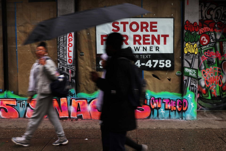 People walk in the rain by commercial real estate for rent along 125th street in the Harlem area of New York City, U.S., February 22, 2023. REUTERS/Shannon Stapleton