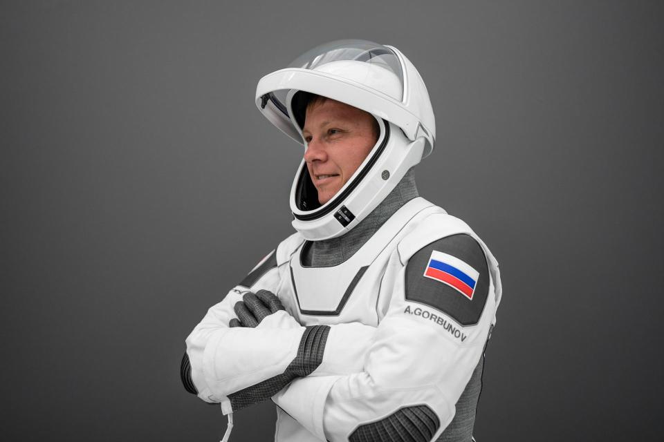 a man in a white spacesuit with a flag on his arm consisting of horizontal stripes of white, blue and red