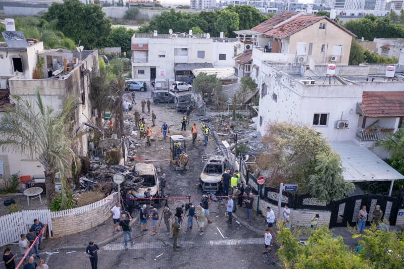 First responders, Israeli security forces and People gather amid debris and damaged vehicles in Kiryat Bialik, following a reported strike by the pro-Iranian Hezbollah movement. Ilia Yefimovich/dpa