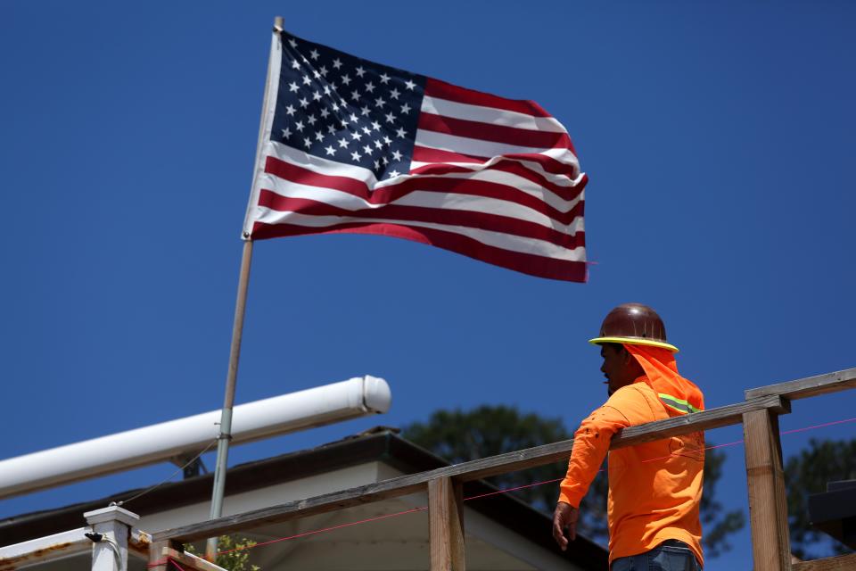 MALIBU,  CA - JULY 3, 2024 - A construction worker pauses to catch a breeze while taking a break from work under an American flag in Malibu on July 3, 2024. (Genaro Molina/Los Angeles Times via Getty Images)