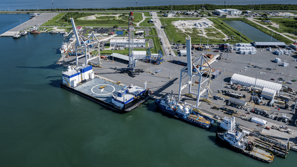  An overhead view of a dock in a sheltered cove, with several large ships moored. 