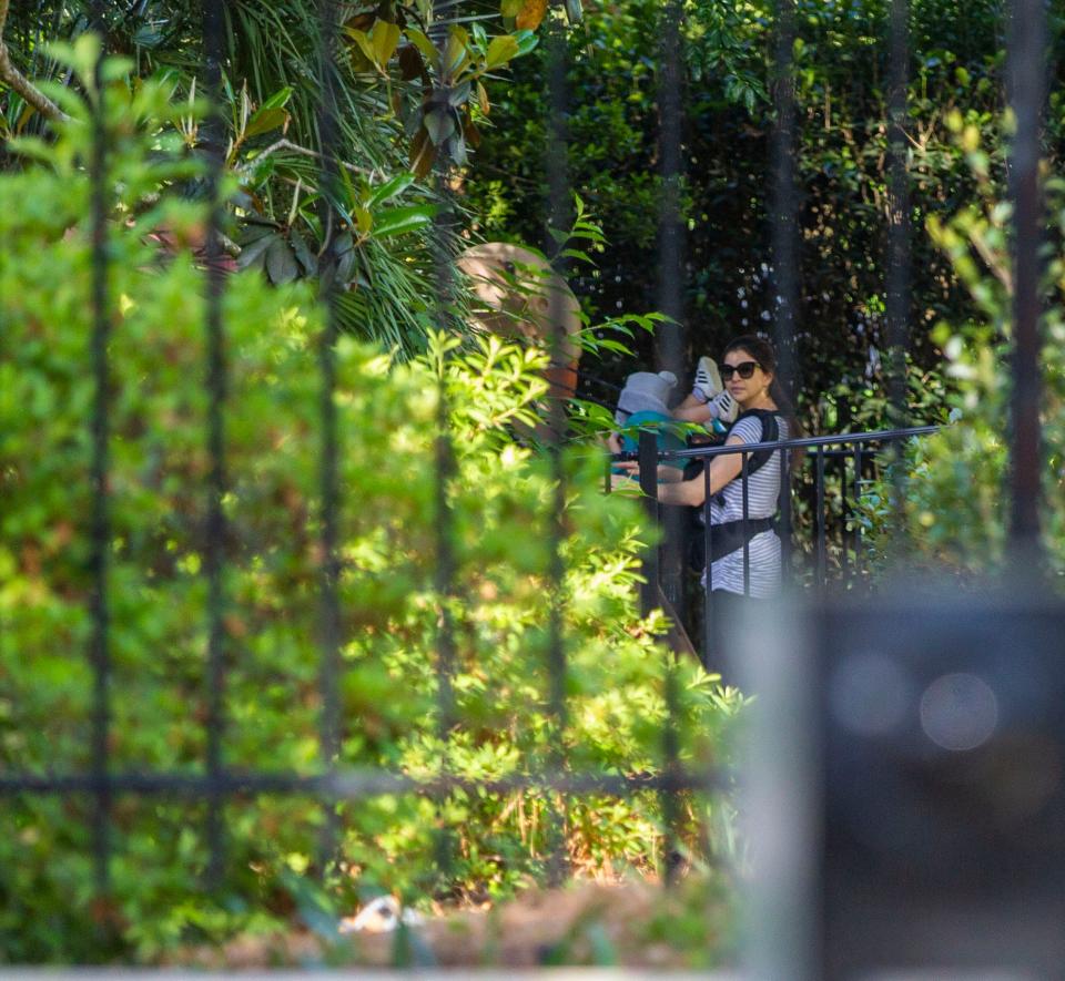 First Lady Casey DeSantis pushes her children on the swings while first responders work to free a protester who cemented his hands in two 55-gallon plastic drums in the driveway of the Governor's Mansion, Friday, April 17, 2020.