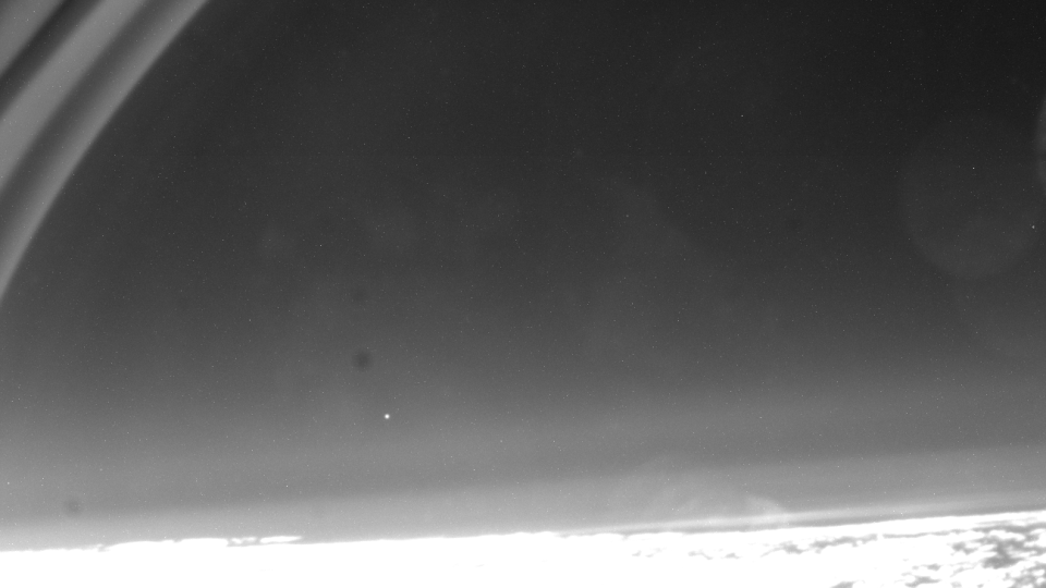  A bright fuzzy low horrizon like a spattering of clouds, a blank black skly with a singular shining point, and what looks like rings crossing on the upper left. 