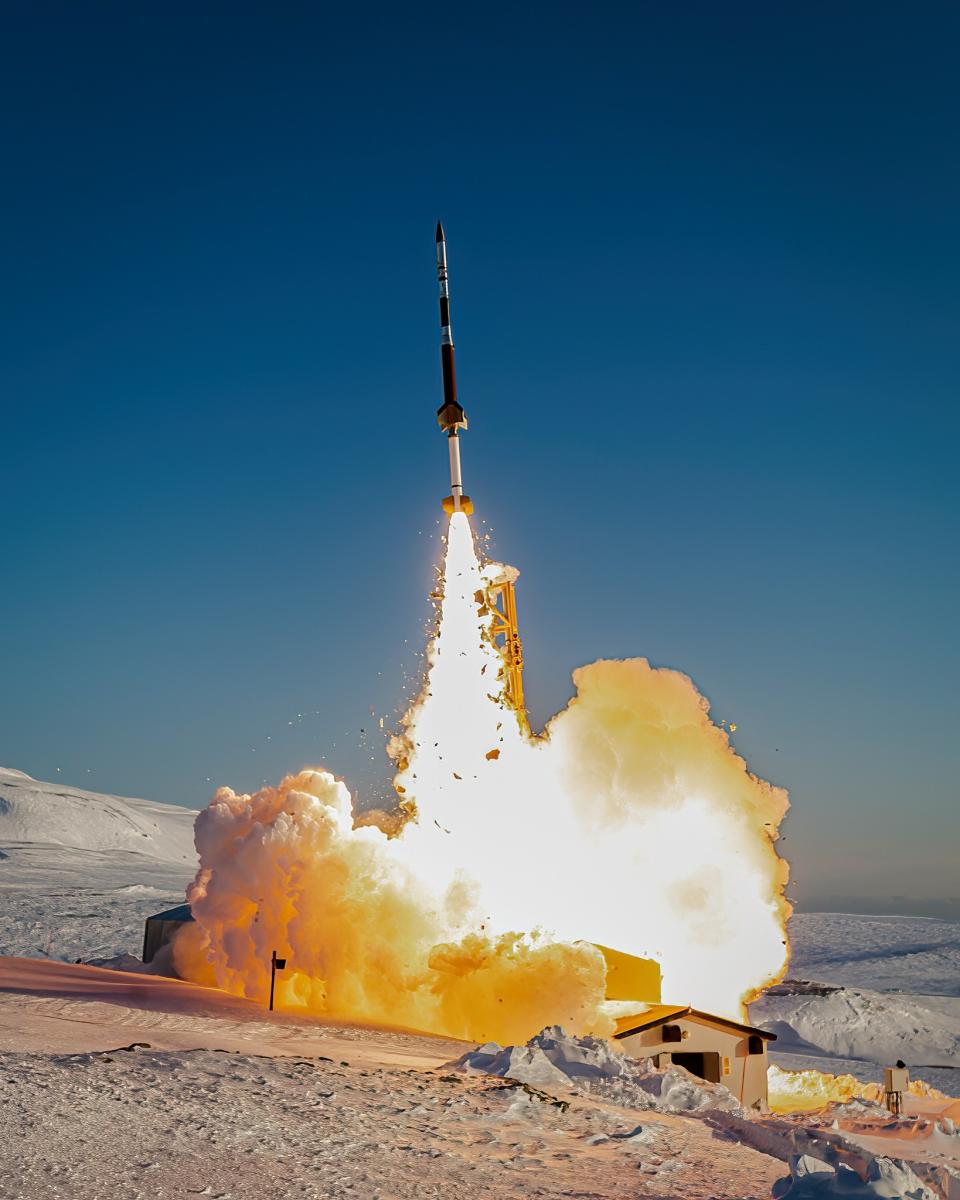 a small rocket lifts off above a snowy landscape