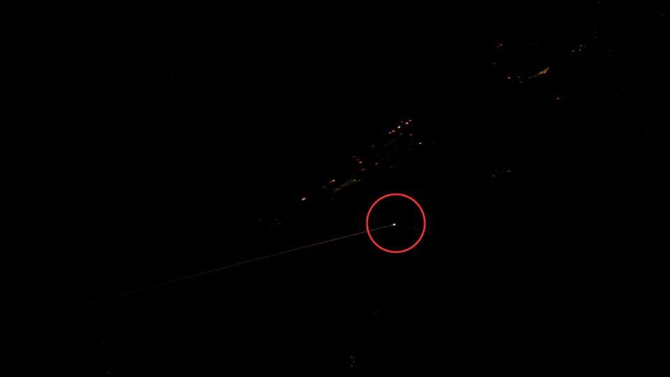  A bright light on earth circled by red, surrounded by darkness, in a picture taken from space. 