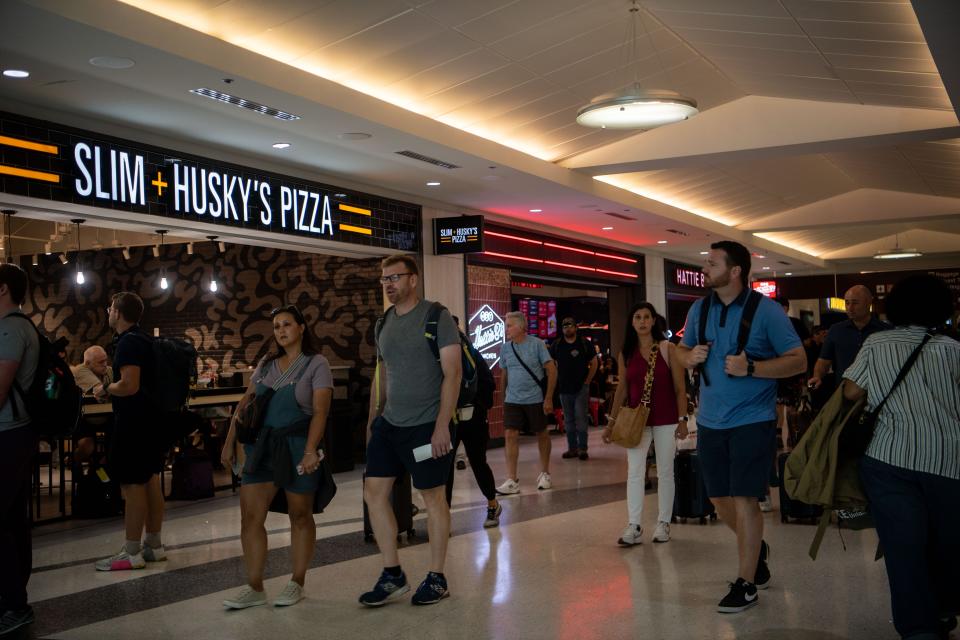 Travelers walk past the Slim + Husky’s Pizza and Hattie B’s at Nashville International Airport in Nashville, Tenn., Wednesday, July 17, 2024.