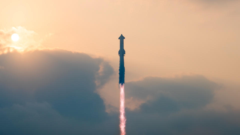 a massive rocket lifts off with a cloudy sky behind it