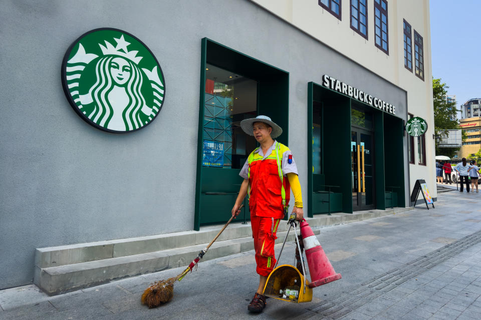 CHONGQING, CHINA - SEPTEMBER 10: A street cleaner walks past a Starbucks Coffee storefront while carrying cleaning tools on September 10, 2024 in Chongqing, China. (Photo by Cheng Xin/Getty Images)