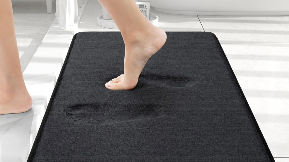 A foot on the black bath mat