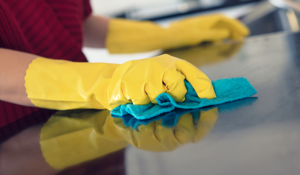 hand wiping down kitchen counter with blue dishcloth.