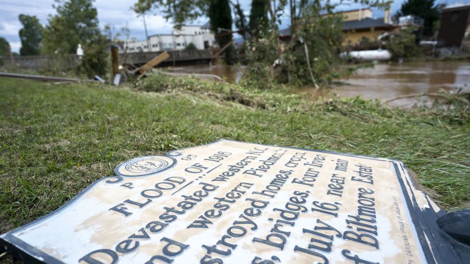 A sign commemorating the flood of 1916 lies on the ground next to a flooded waterway near Biltmore Village. - Sean Rayford/Getty Images