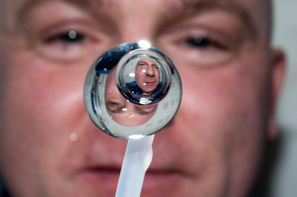 A water droplet in microgravity with a person behind.