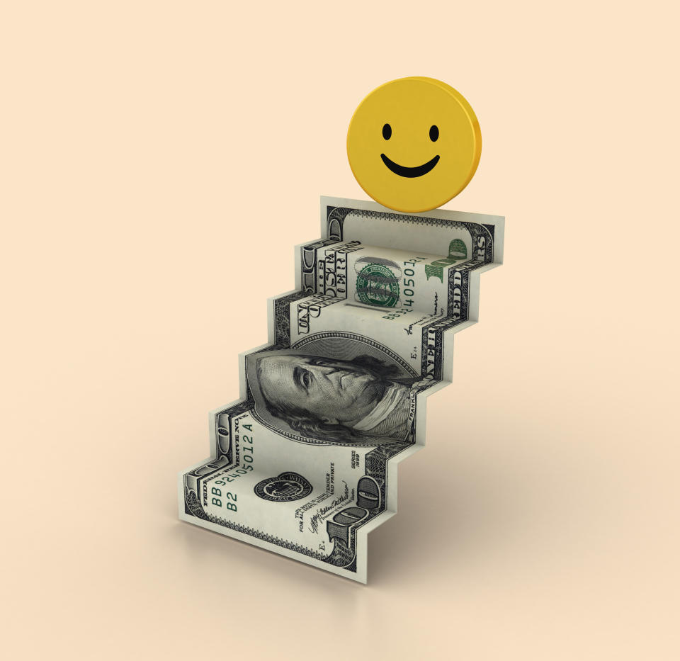 A dollar bill folded into a staircase shape with a yellow happy-face disc at the top.