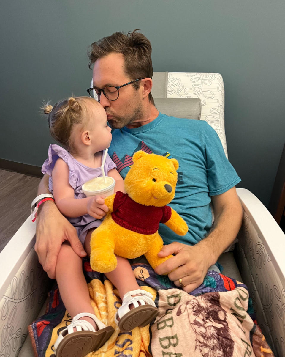 Michael Warren kisses his daughter, seated in his lap, on the forehead, as she hold a Winnie the Pooh stuffed animal (Michael Warren)