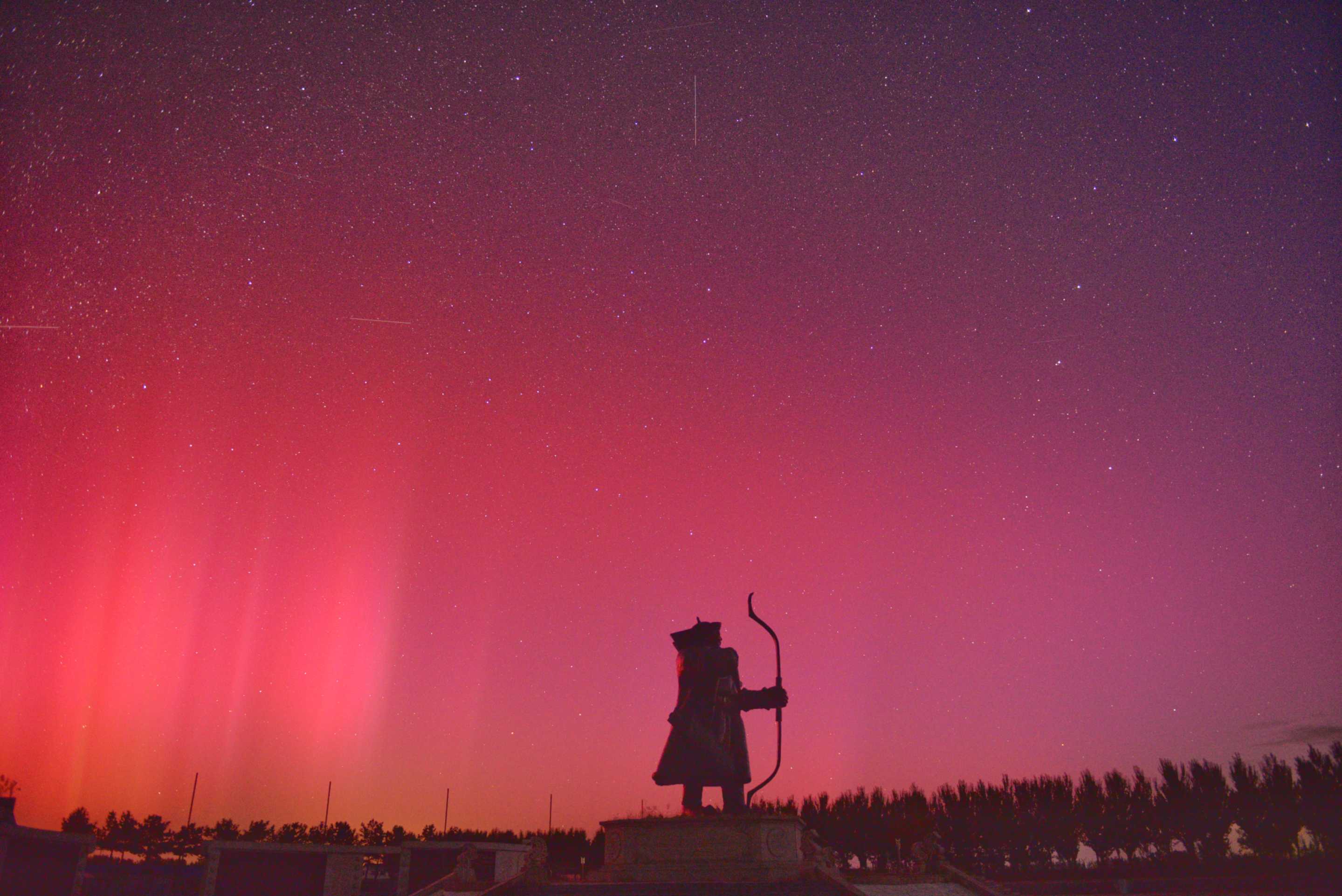 Aurora borealis behind silhouette of top of Great Wall.