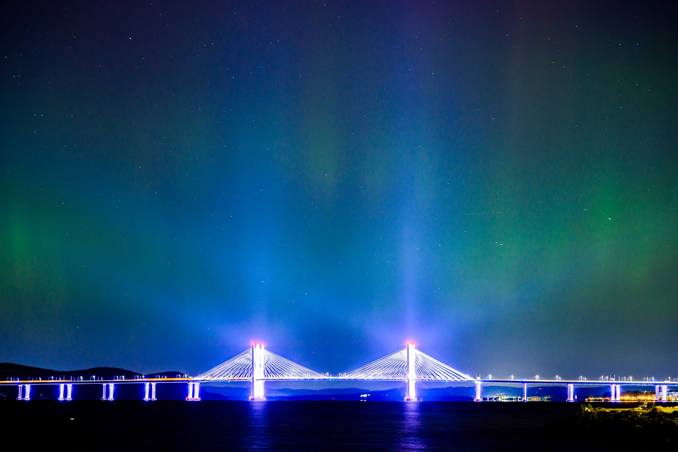 Northern lights behind illuminated bridge.