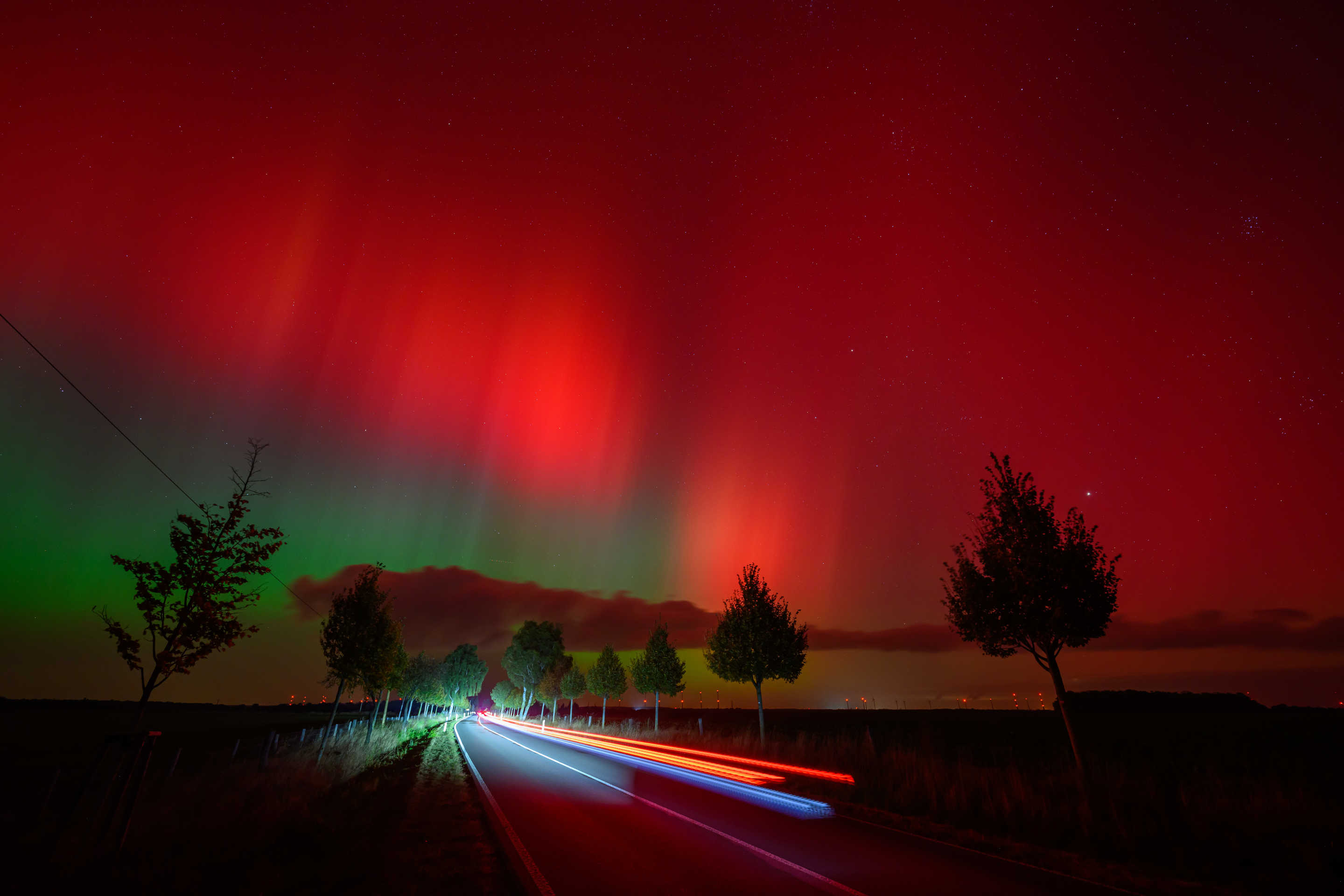 dpatop - 10 October 2024, Brandenburg, Lietzen: Northern lights glow in the night sky above a road in eastern Brandenburg, Germany. (Patrick Pleul/picture alliance via Getty Images)