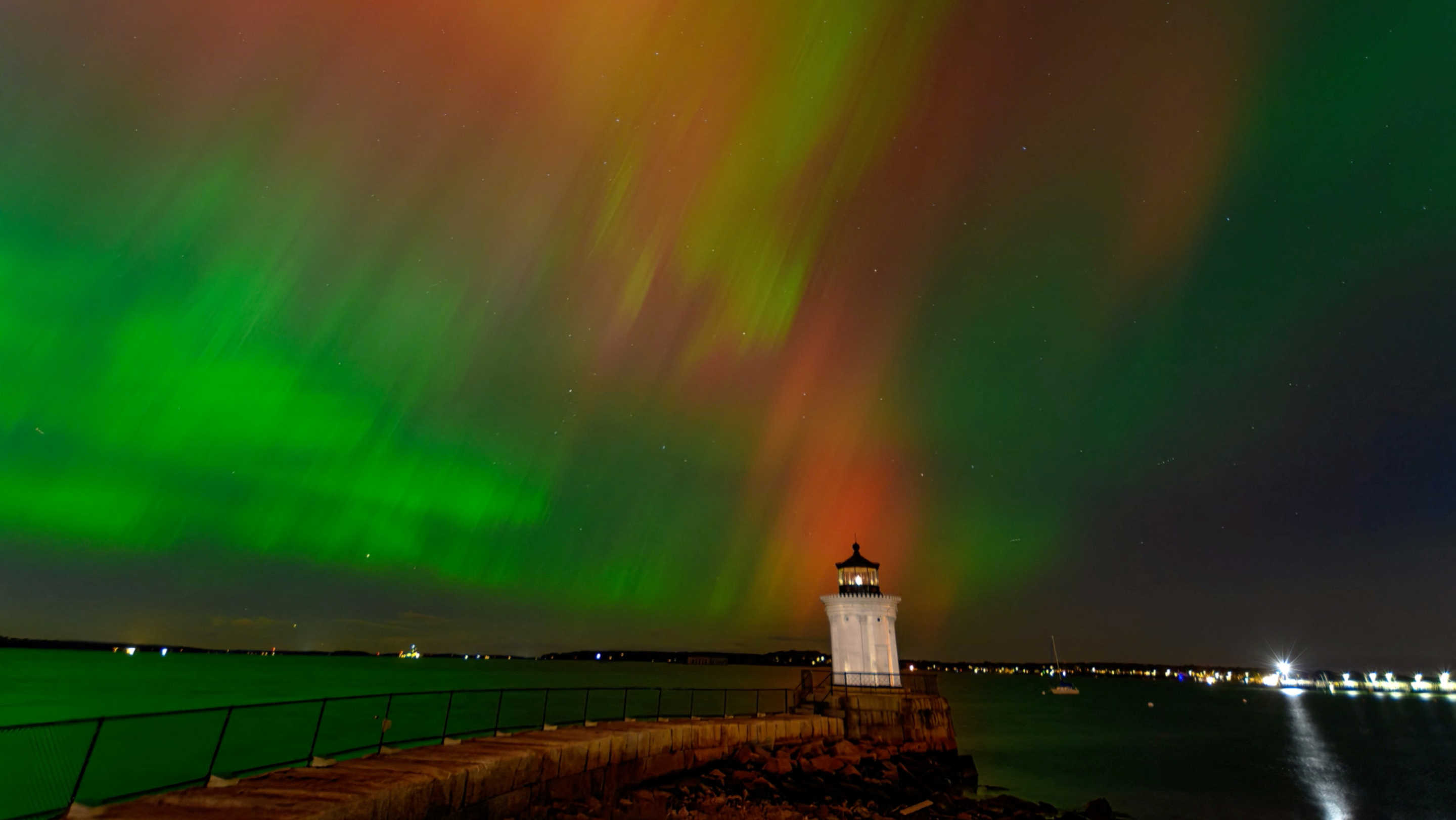 Aurora borealis against lighthouse and body of water.