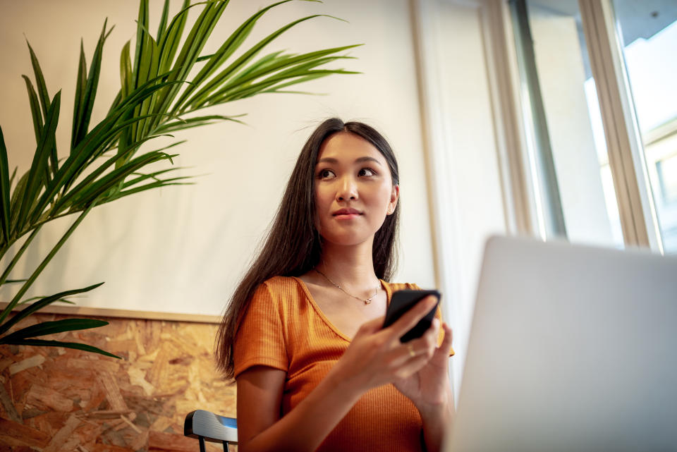 Woman using mobile phone and laptop.