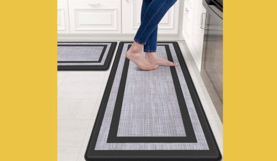 feet on a gray and black kitchen mat, with a yellow background