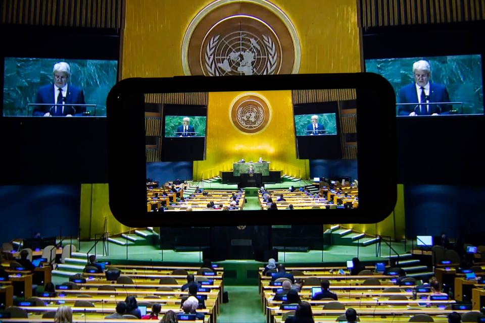 view of the united nations general assembly with several screens. marc garneau is visible on the screens