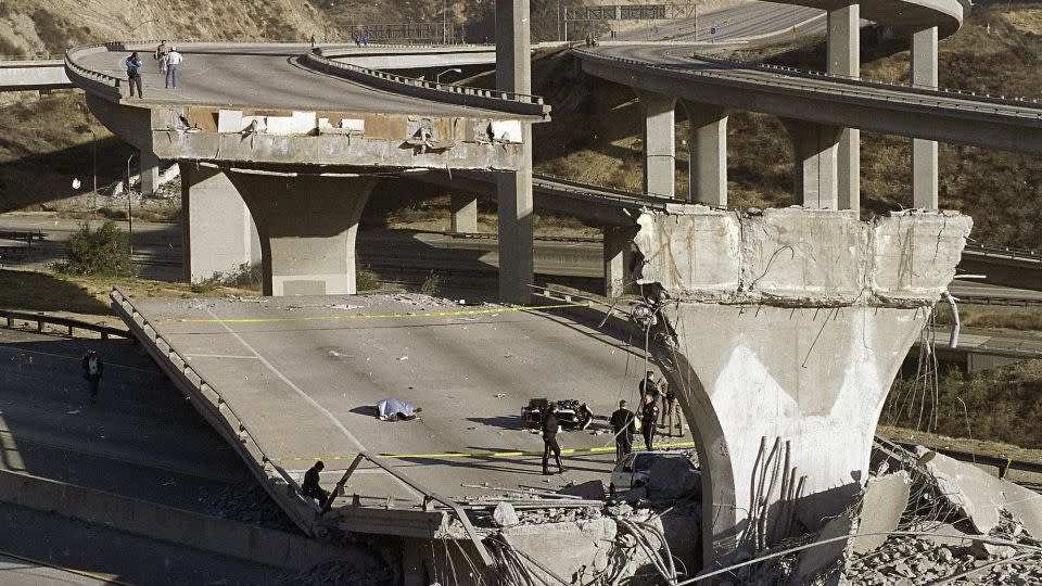 The covered body of Los Angeles Police Officer Clarence Wayne Dean lies near his motorcycle which plunged off the State Highway 14 overpass that collapsed onto Interstate 5 during the Northridge earthquake. - Douglas C. Pizac/AP