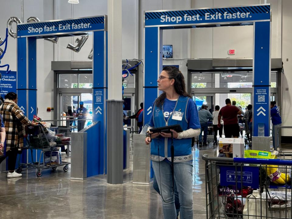 A Sam's Club employee stands ready to process shoppers' orders on a mobile tablet.