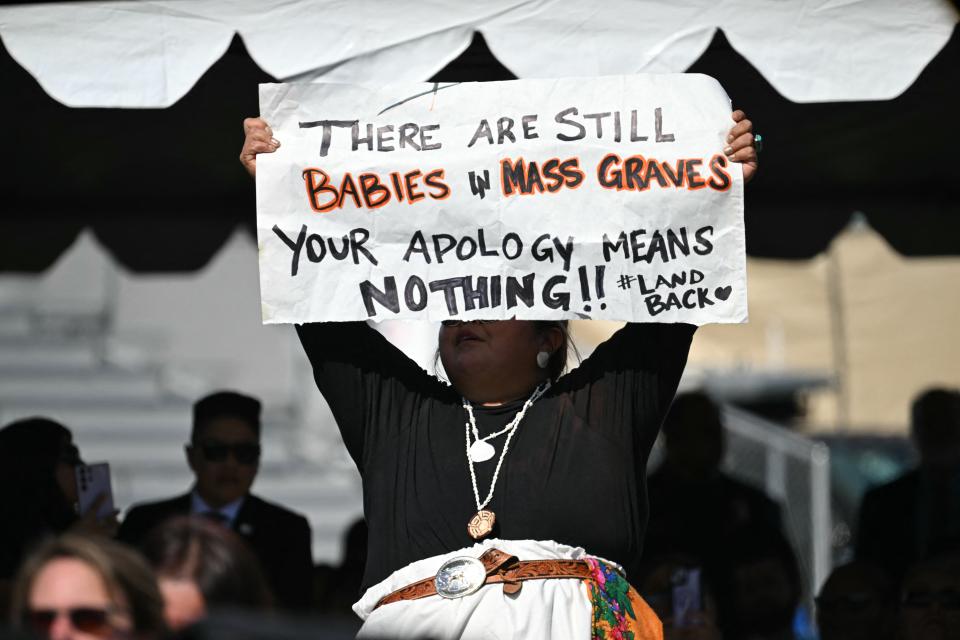 A protester holds a sign as Biden speaks at the Gila Crossing Community School. 