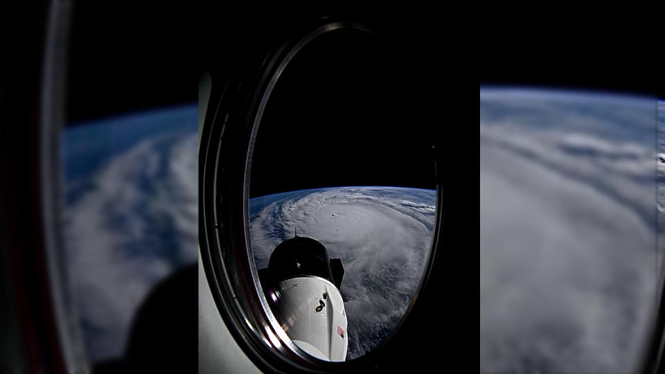  View through an orbiting spacecraft's window showing a large hurricane on earth below, with a white space capsule in the foreground. 