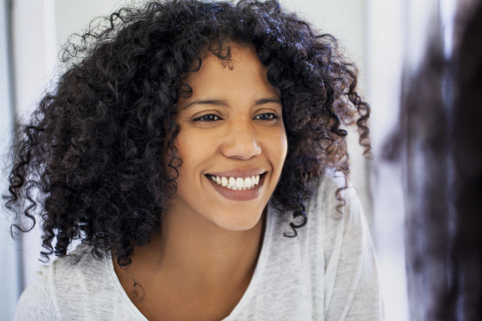 A woman smiling and looking into a mirror. 