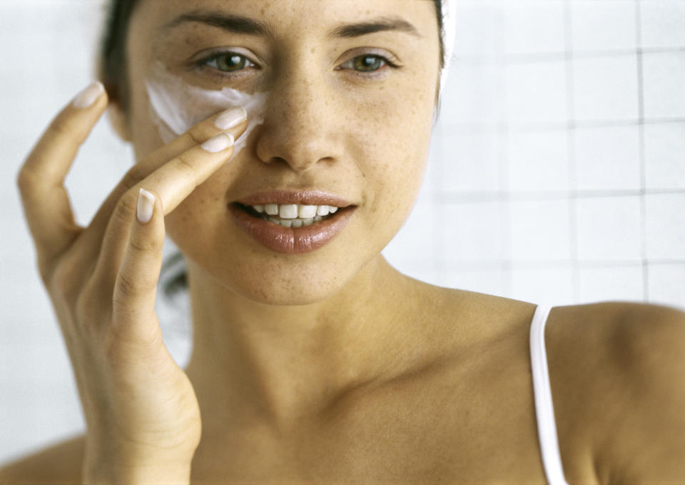 Photo of a woman applying cream under the eyes. 