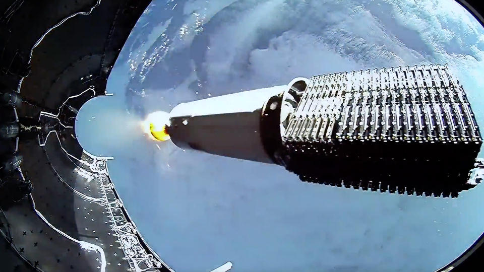  A piece of fairing to the left of a set of stacked starlink satellites. earth is below. 