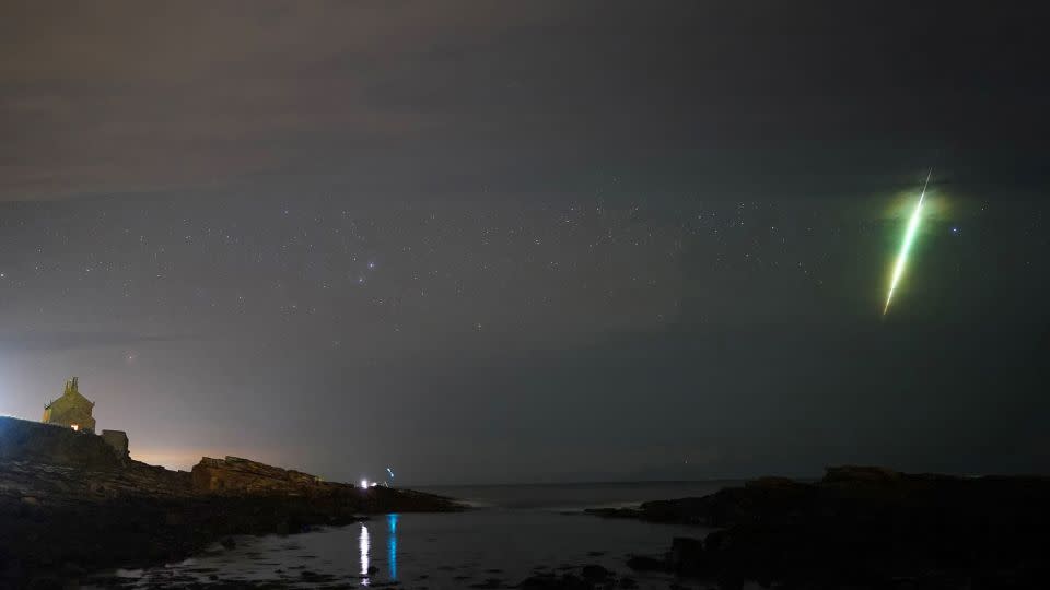 A meteor streaks across the sky during the Draconid meteor shower as seen over Howick rocks in Northumberland in northeast England in October 2021. - Owen Humphreys/PA Media/FILE