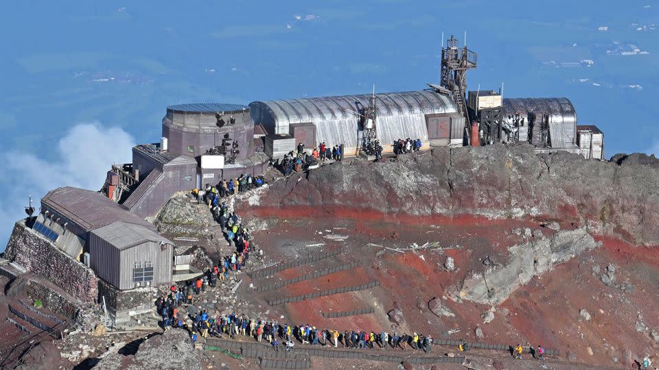 This aerial view shows climbers lining up to take a photo on the Kengamine summit of Mount Fuji on August 10, 2024. - Stringer/Kyodo News/Getty Images