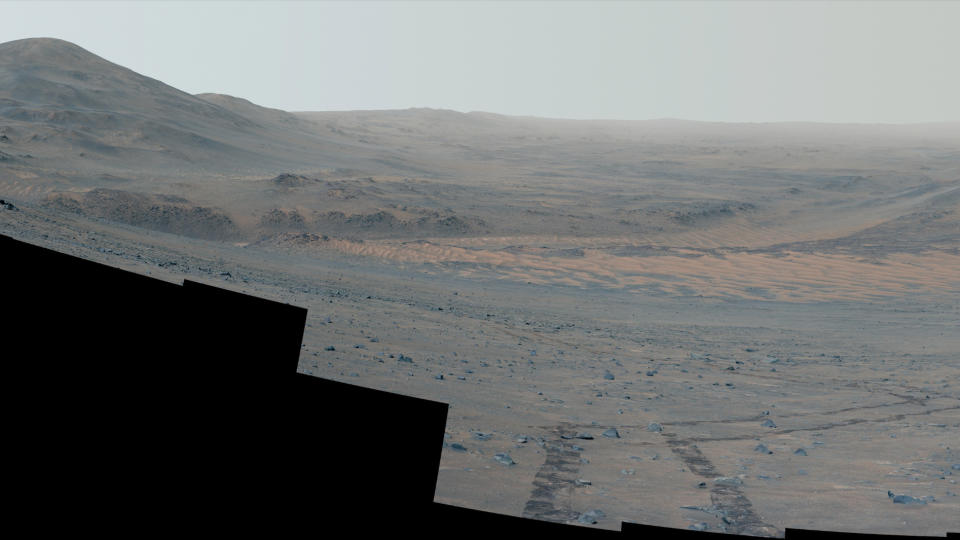  Looking down the slope of a crater rim on mars, with rover tracks in the foreground. 