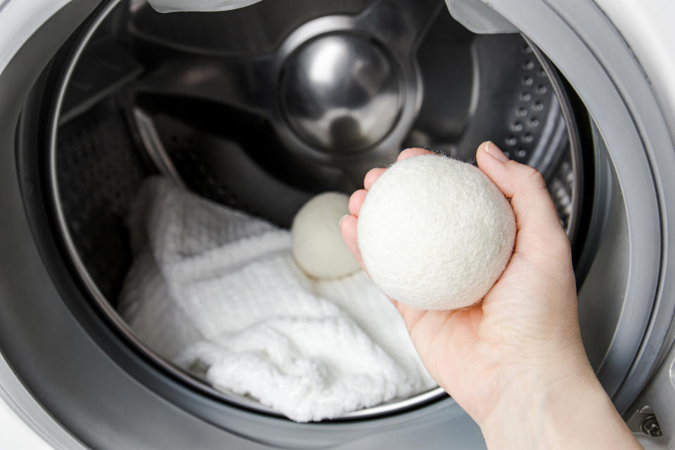 hand holding a wool dryer ball in front of an open dryer