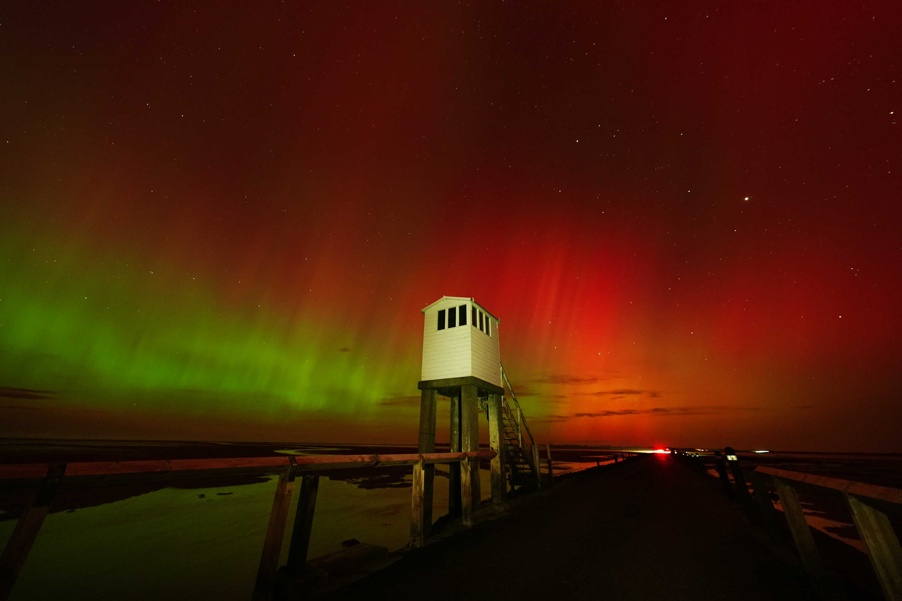 Aurora borealis behind elevated hut.