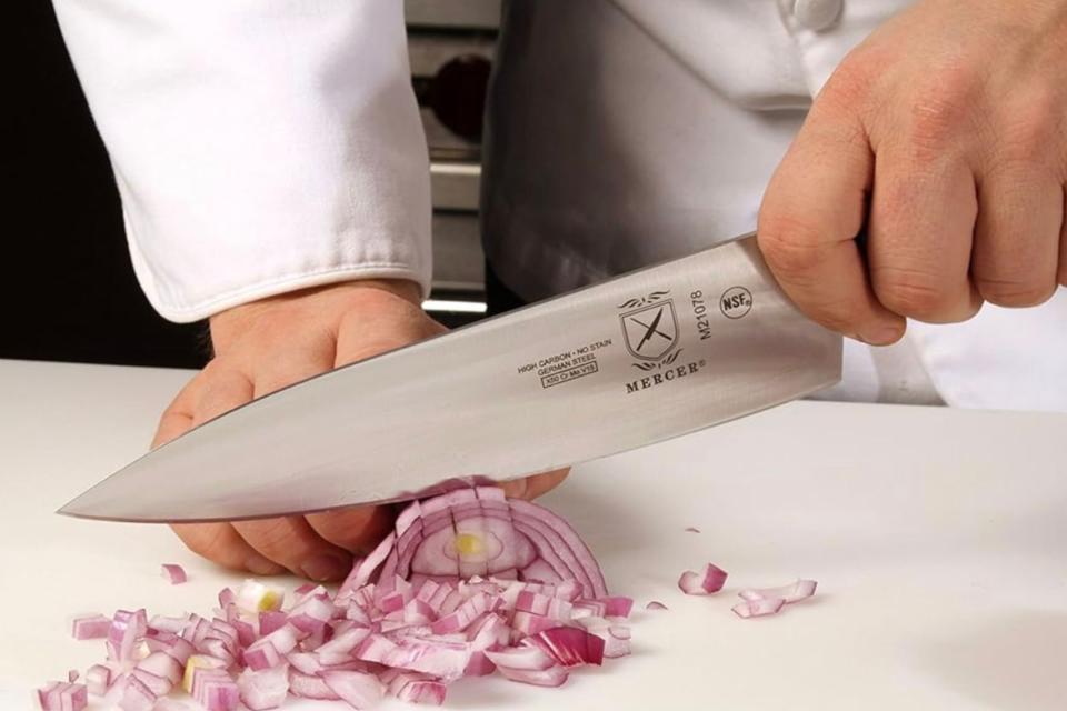 Chef chopping a red onion with a Mercer knife.