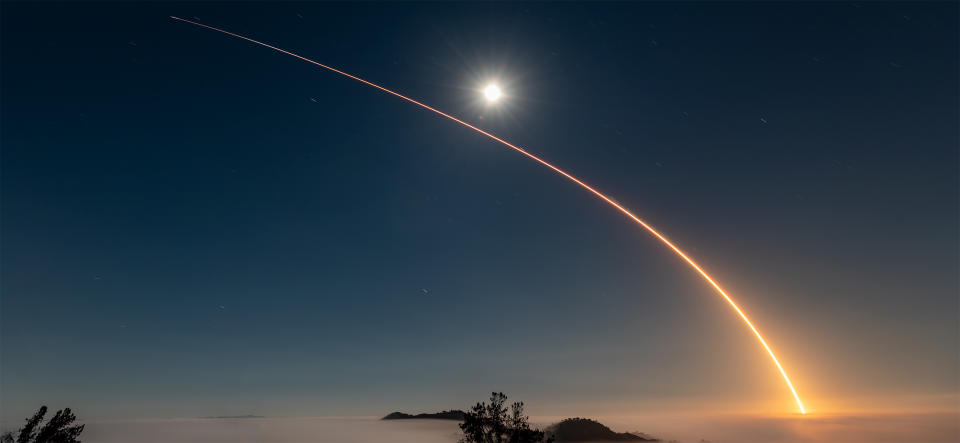  A rocket launch carves an orange arc into a dark night sky in this long-exposure photo. 