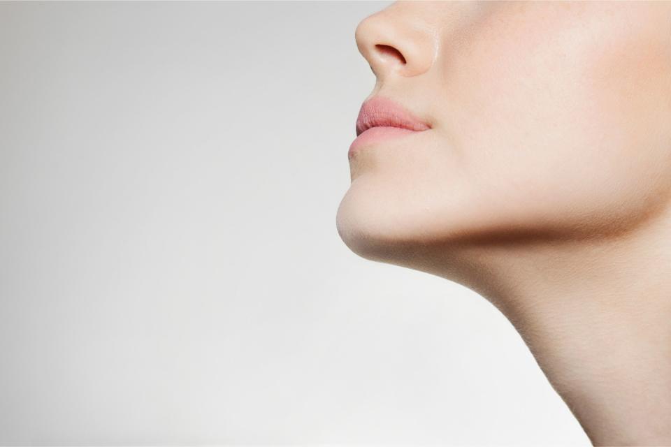 A woman's face against a beige background.