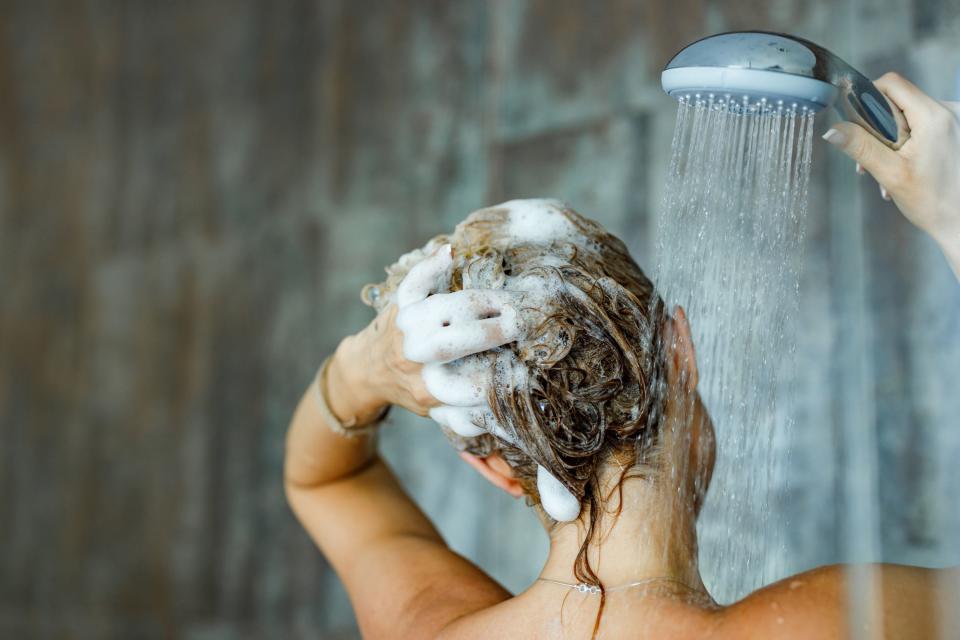 Woman showering with shampoo lather in her hair.