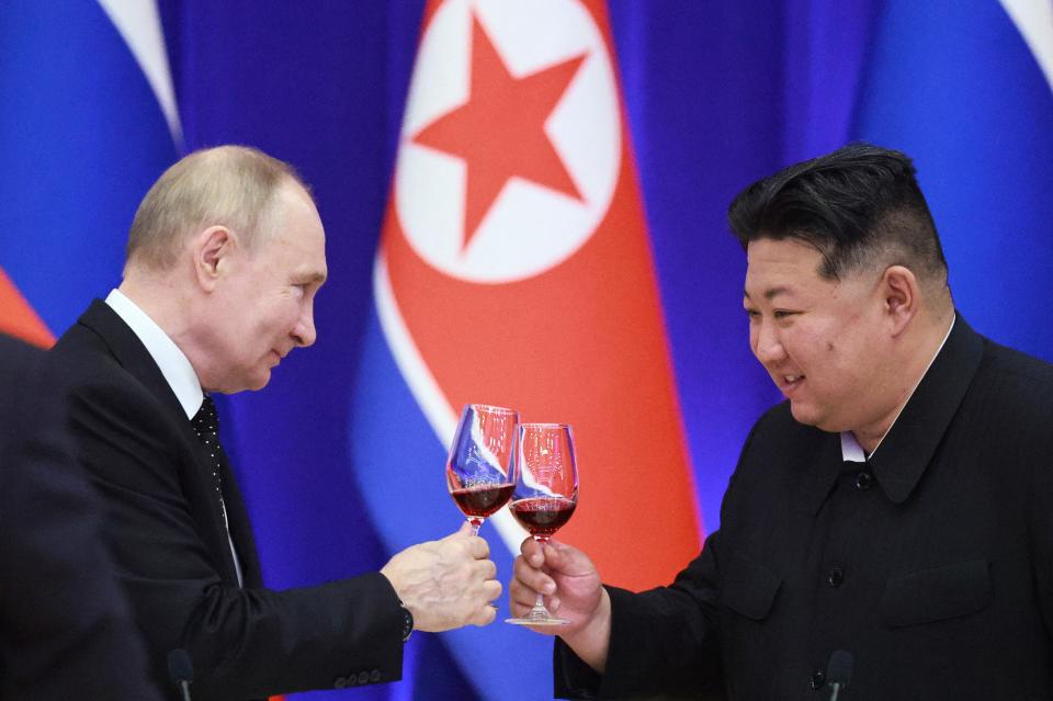 Vladimir Putin and Kim Jong Un appear to toast with wine glasses.